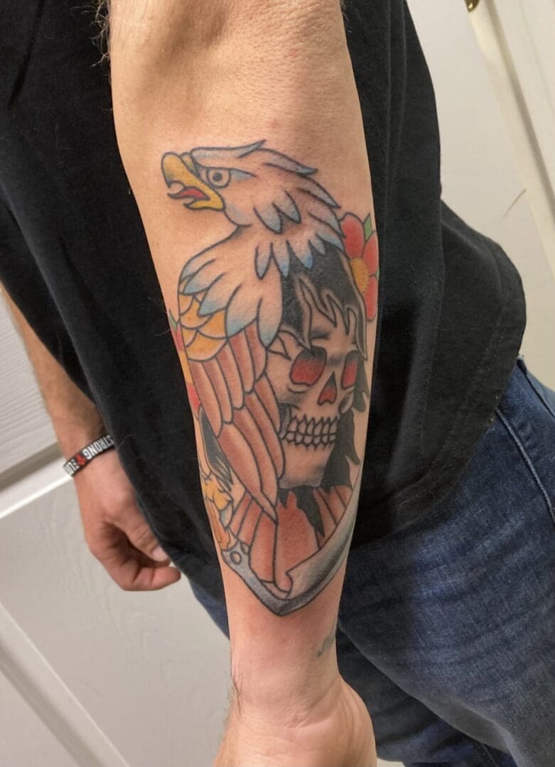 an egal and skull tattoo on the backside of the arm