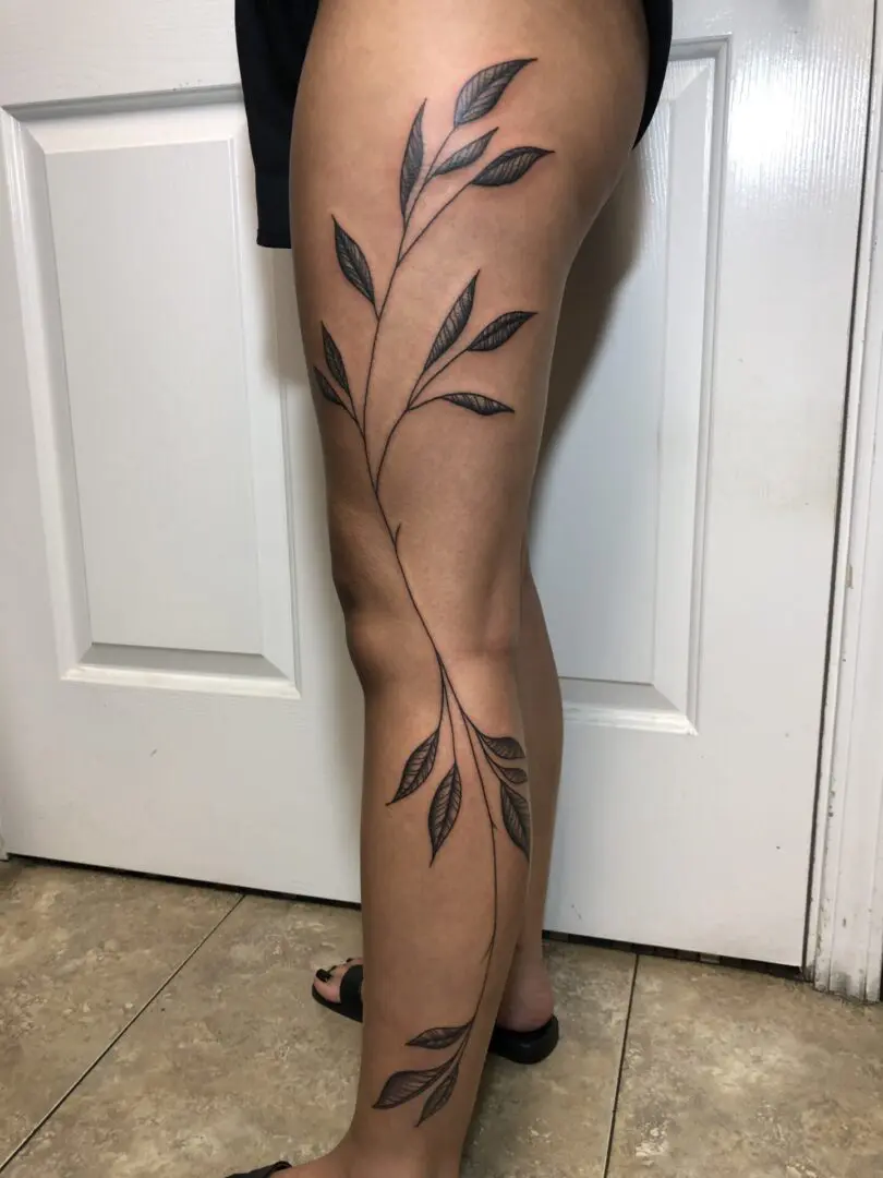leaves tattoo on the full leg of a woman