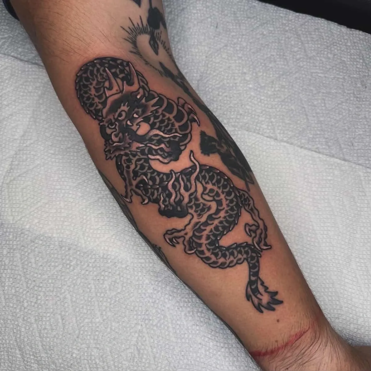 Dragon tattoo on forearm with intricate details.