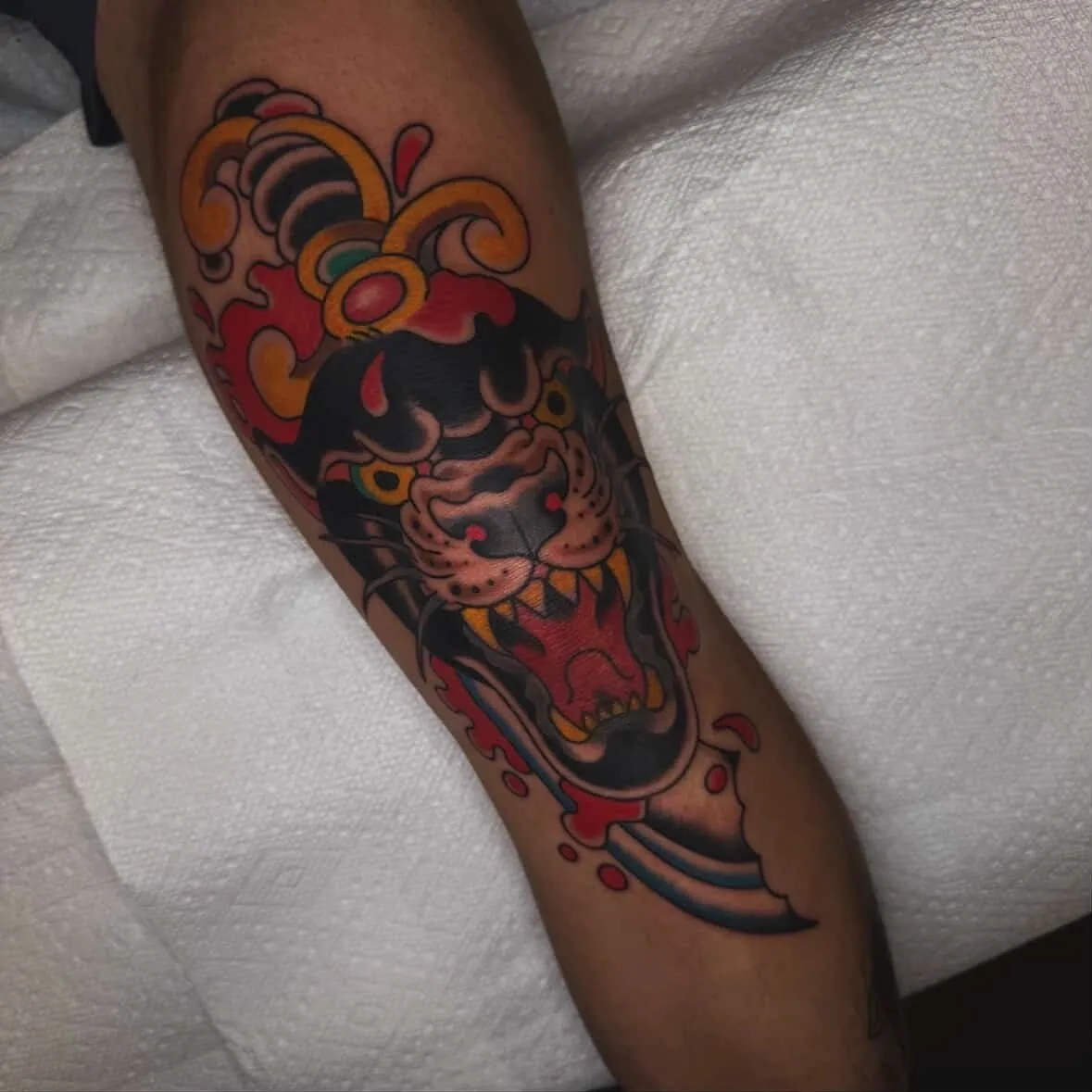 Tattoo of panther with dagger on leg.