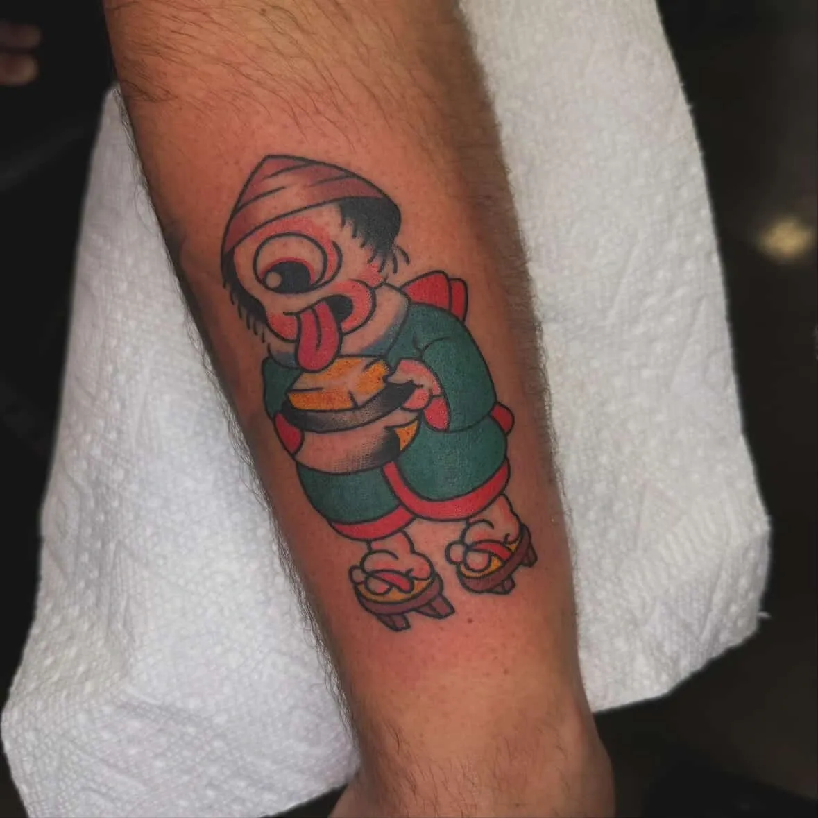Colorful cartoon character tattoo on forearm.
